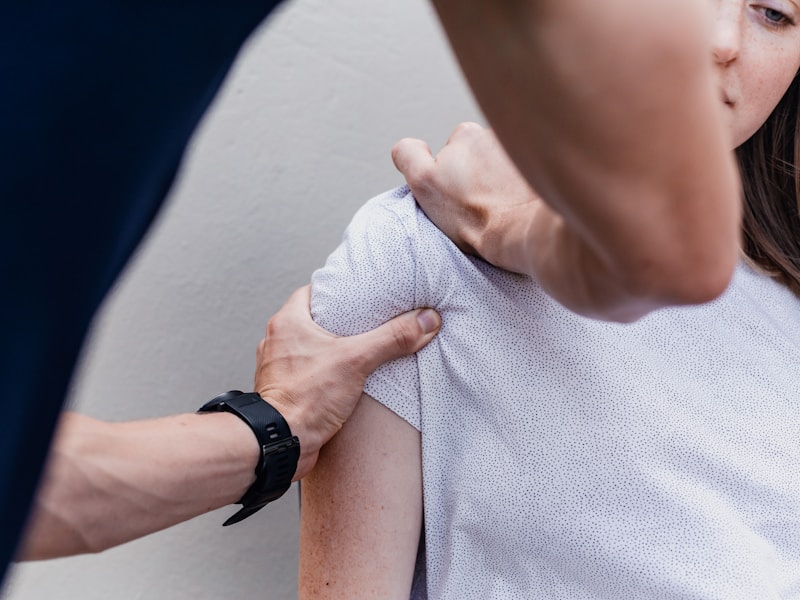 A therapist assessing a seated client's shoulder during an appointment