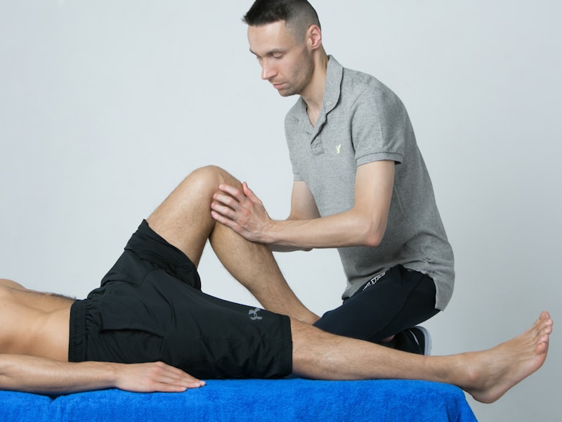 A therapist assessing the range of motion in a client's knee and hip on a treatment table